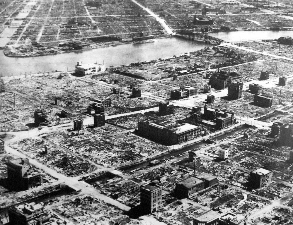 Aerial view of a devastated urban landscape post-disaster, with sparse buildings and debris visible. The image illustrates the extent of destruction, relevant for discussions on historical disasters.